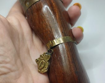 May include: A wooden and brass hand-shaped bottle stopper with a gold-colored fish design on the top and a floral design on the bottom.
