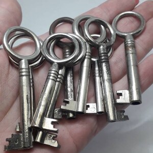May include: A collection of vintage silver keys with ornate designs. The keys are arranged in a hand, with the keyholes facing the viewer.