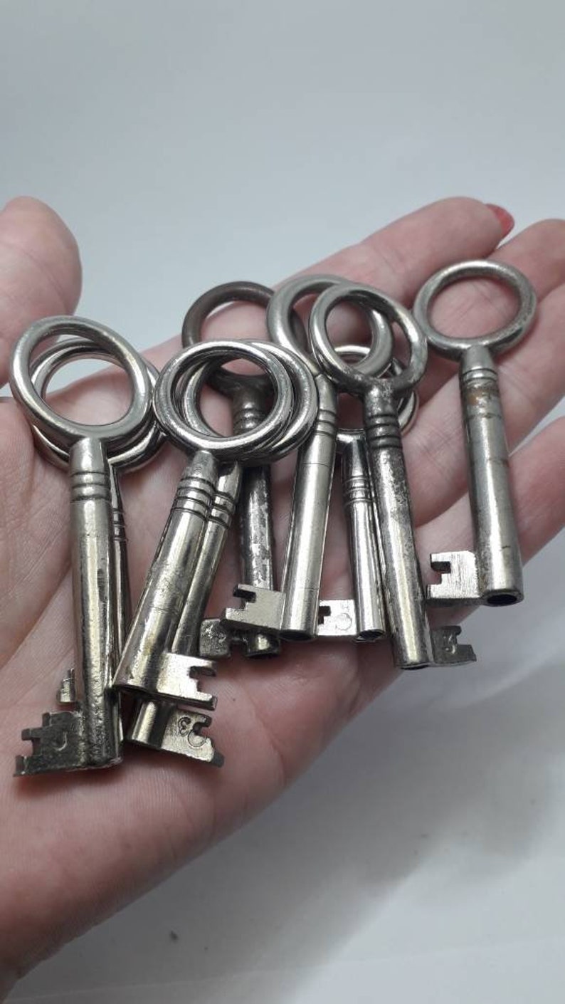 May include: A collection of vintage silver keys with ornate designs. The keys are arranged in a hand, with the keyholes facing the viewer.