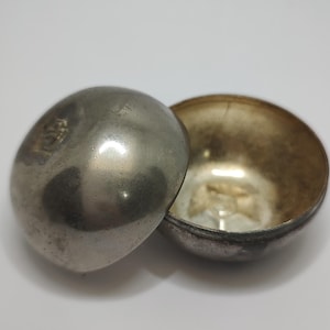 May include: A silver metal bowl with a lid. The bowl is slightly tarnished and has a gold interior.