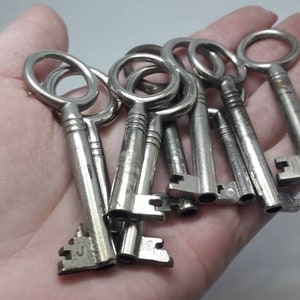 May include: A collection of vintage silver keys with intricate designs and different sized keyholes. The keys are held in a hand.