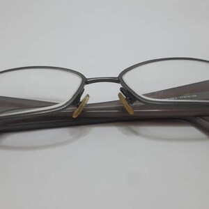 May include: A pair of gray metal eyeglasses with a rectangular frame and brown arms.