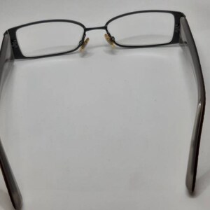 May include: A pair of black metal eyeglasses with rectangular frames and clear lenses.