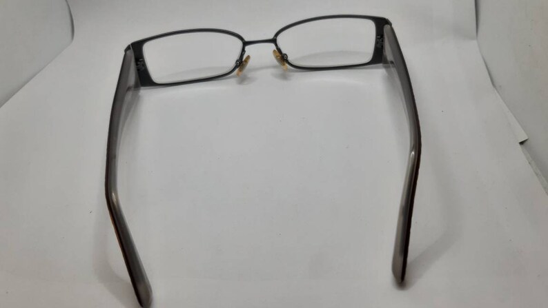 May include: A pair of black metal eyeglasses with rectangular frames and clear lenses.