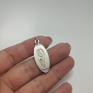 May include: Silver oval pendant with a detailed image of the Virgin Mary praying.