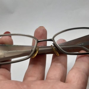 May include: A pair of brown metal eyeglasses with a rectangular frame. The glasses have a subtle sheen and are in good condition.