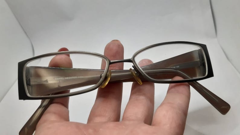 May include: A pair of brown metal eyeglasses with a rectangular frame. The glasses have a subtle sheen and are in good condition.