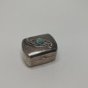 May include: A small, silver, rectangular box with a hinged lid. The lid features a turquoise stone set in a silver design.