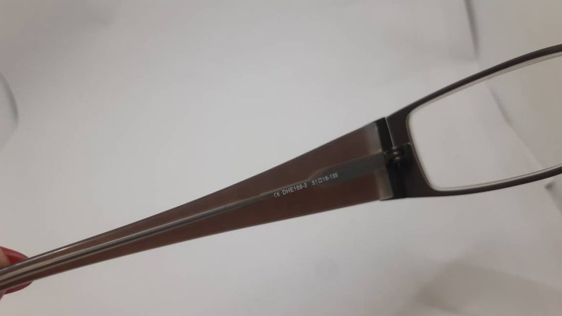 May include: Brown rectangular glasses with a metal frame and clear lenses. The glasses have the text "CE DH2138-2 51□16-138" printed on the frame.