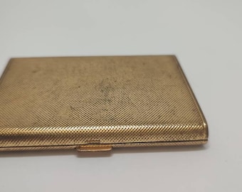Könnte beinhalten: Ein goldfarbenes Metall-Zigarettenetui mit einer strukturierten Oberfläche.