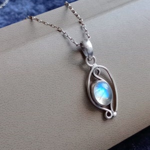 May include: A silver chain necklace with a pendant featuring a round iridescent moonstone set in a delicate silver frame.