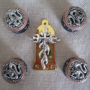 May include: Four black and copper guitar knobs with silver dragon designs and a gold metal guitar plate with a silver cross and flame design.