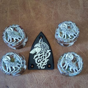 May include: A collection of decorative items featuring wolf designs. Includes four round, lidded boxes and a black, triangular plate. The boxes and plate have a silver wolf design on a brown and white background.