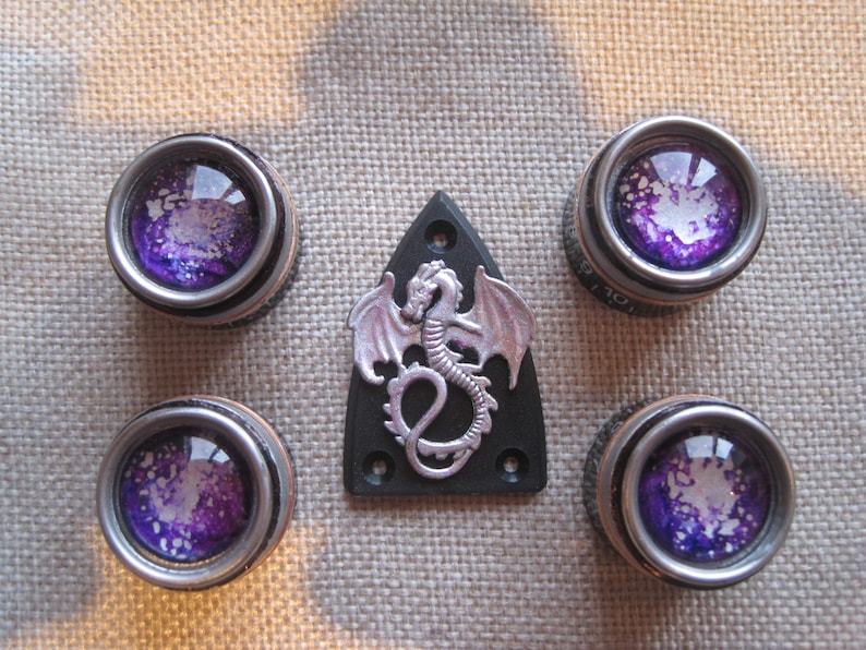 May include: Four silver and purple knobs with a silver dragon on a black guitar pickguard.