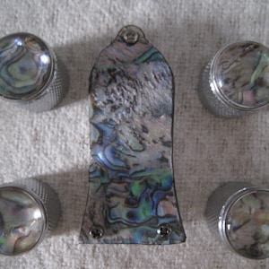 May include: Five silver knobs with a mother-of-pearl inlay. The knobs are arranged in a semi-circle around a larger, rectangular piece of mother-of-pearl.