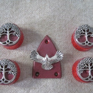 May include: Set of five red knobs with silver tree of life designs and a red guitar pickguard with a silver flying bird design.