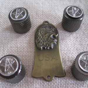 May include: A set of four black knobs with a silver five-pointed star design and a brass guitar plate with an eagle head and the word "USA" engraved on it.