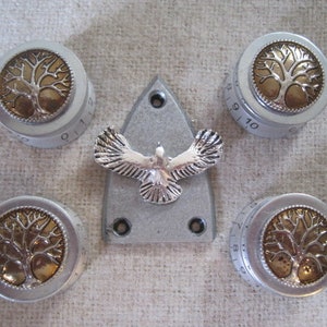 May include: Five silver knobs with a tree of life design in gold. The knobs are numbered 0-10. A silver plate with a dove design is in the centre.