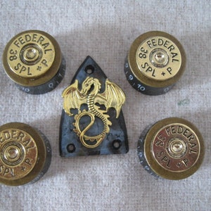 May include: Four gold-colored guitar knobs with the text "FEDERAL 38 SPL +P" and a black guitar pickguard with a gold dragon design.