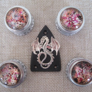 Può includere: Quattro manopole per chitarra argentate con un design astratto colorato e una manopola a forma di drago argentata su sfondo nero.