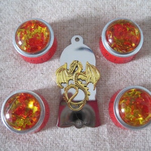 Op de afbeelding: Vijf rode en zilveren knopbedekkingen met amberkleurige glazen inzetstukken. De middelste knopbedekking heeft een gouden draakontwerp.