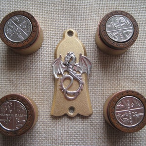 Peut inclure: Cinq boutons ronds de couleur dorée avec un motif de dragon argenté au centre. Les boutons ont un anneau extérieur brun avec un motif décoratif.