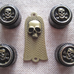 May include: Set of six gold-tone skull and crossbones guitar knobs with a matching gold-tone skull guitar pickguard.