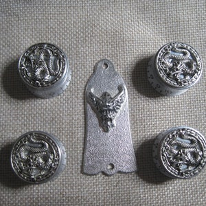 May include: Set of five silver-toned guitar knobs with a dragon design and a silver-toned guitar pickguard with a bird design.