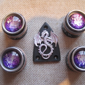 May include: Set of five silver guitar tuning knobs with purple and white galaxy-themed designs. The knobs are surrounded by a silver trim. A silver dragon pickguard is also included.