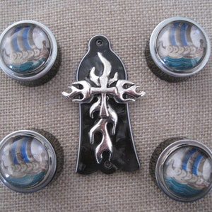 Puede incluir: Conjunto de seis botones de guitarra plateados con un diseño de cruz negro y plateado. Cada botón tiene una parte superior de vidrio transparente con una imagen de un barco vikingo navegando en el agua.