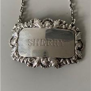 以下が含まれることがあります： 前面に「SHERRY」と刻まれた、装飾的なデザインの銀製のボトルラベルです。