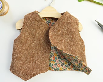 May include: A brown tweed vest with a floral print lining. The vest has a V-neck and is sleeveless.