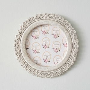 May include: A beige crocheted picture frame with a white background and the text "Wedding Day" repeated in a circle.