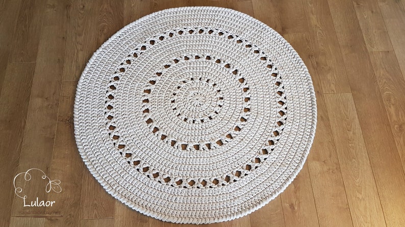May include: A white crocheted round rug with a spiral pattern and openwork design.