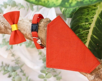 May include: A red bow tie with a yellow center, a red bandana, and a red cat collar with a bell.
