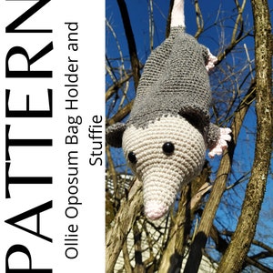 K&ouml;nnte beinhalten: Ein geh&auml;kelter grauer und rosa Opossum, der an einem Baumzweig h&auml;ngt. Der Opossum hat schwarze Augen und eine rosa Nase. Der Text "PATTERN ollie Opossum Bag Holder and Stuffie" befindet sich auf der linken Seite des Bildes.