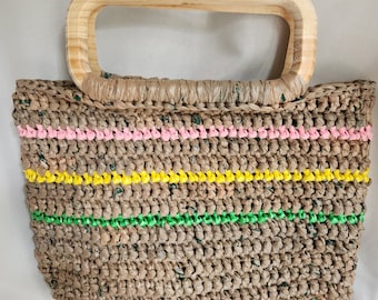 May include: A woven tote bag with a light brown body and a light wood handle. The bag features horizontal stripes of pink, yellow, and green. The bag is made of a woven material.
