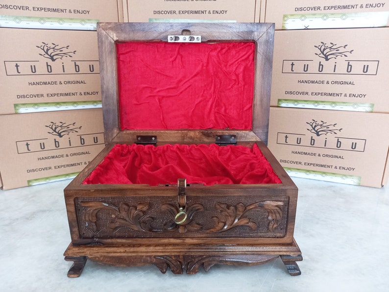 May include: An open wooden box with a red velvet lining. The box has intricate carvings on the front and sides. The box is labeled "tubibu" and "Handmade & Original".