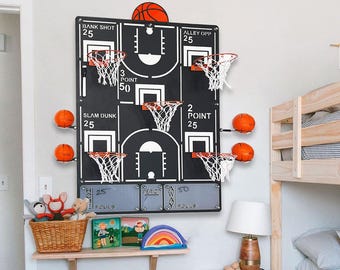 May include: A black basketball wall game featuring multiple hoops and an orange basketball. The game board is marked with scoring sections like "Bank Shot" and "Alley Opp." Several orange basketballs are mounted on the wall. The game is designed for indoor play.