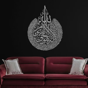 Puede incluir: Un sofá de terciopelo burdeos con dos cojines blancos frente a una pared negra con una calcomanía de pared de caligrafía islámica plateada. La calcomanía presenta las palabras árabes "Allah" y "Muhammad" en un diseño circular.