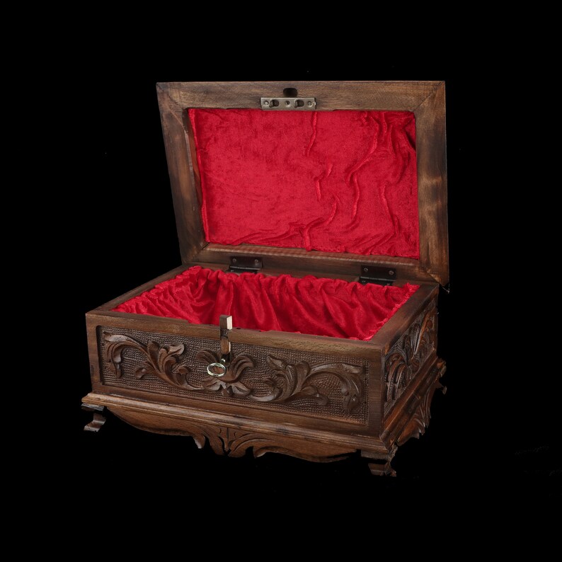 May include: A wooden box with intricate carvings and a red velvet lining. The box is open and the lid is propped up.