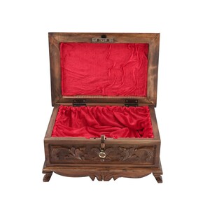 May include: A wooden box with intricate carvings and a red velvet lining. The box has a hinged lid and a decorative metal handle.