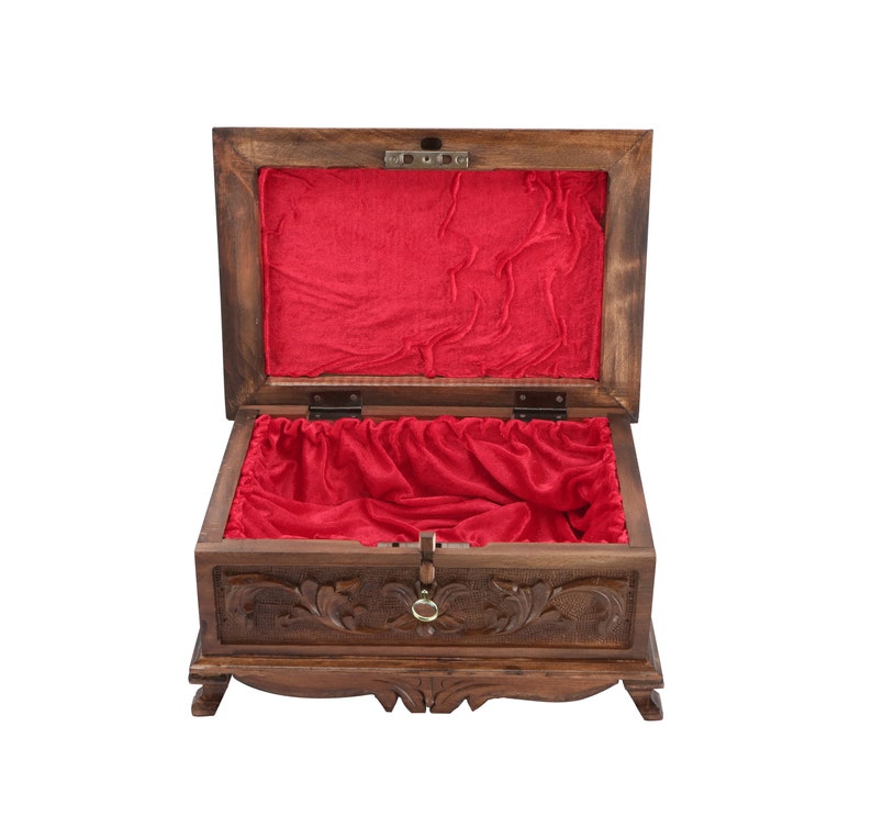 May include: A wooden box with intricate carvings and a red velvet lining. The box has a hinged lid and a decorative metal handle.