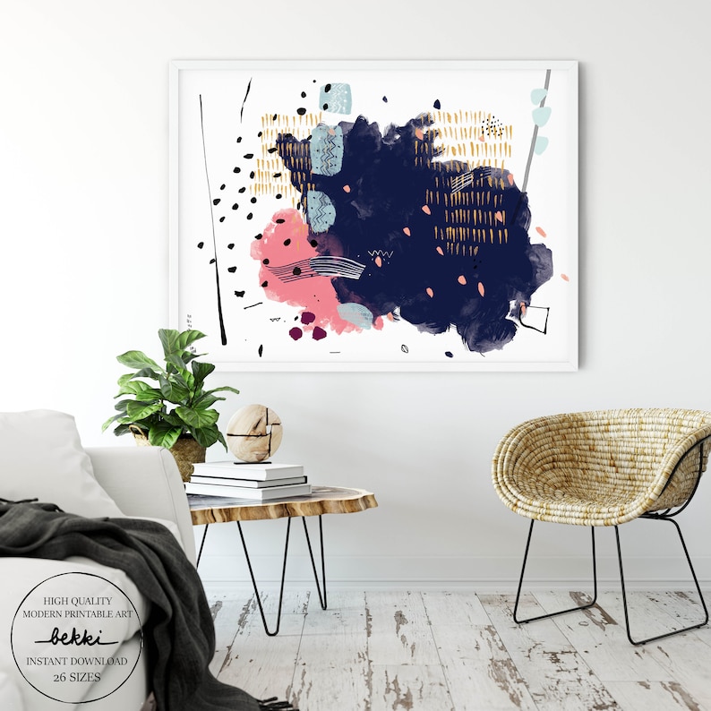 May include: Abstract art print featuring a navy blue, pink, and gold colour scheme. The print incorporates geometric shapes and brushstrokes against a white background. The print is framed and displayed on a white wall.