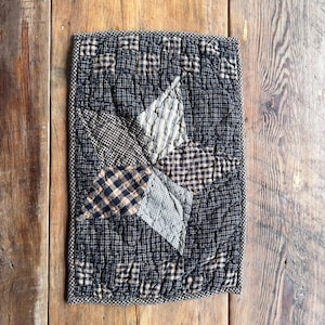 May include: A black and white quilted throw pillow with a star design. The pillow is made of a soft, textured fabric and has a subtle sheen.