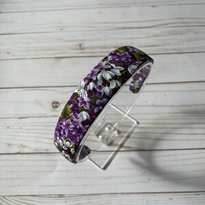 May include: A purple and white floral headband with a wide band.