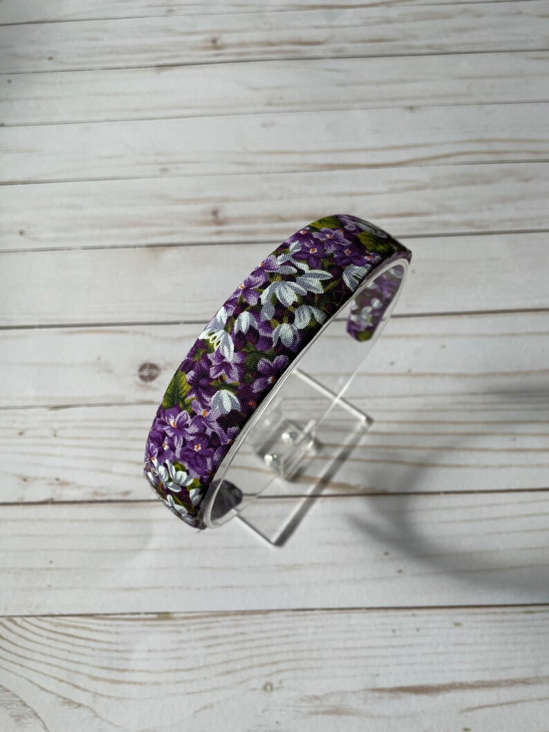 May include: A purple and white floral headband with a wide band.