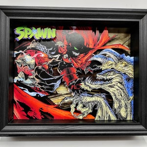 Può includere: Una stampa d'arte di fumetti incorniciata con Spawn, un supereroe rosso e nero, che combatte contro una creatura mostruosa con squame blu e bianche. La stampa è intitolata "Spawn" in lettere verdi.