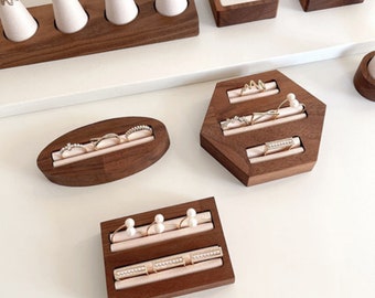 May include: Wooden ring display stands with multiple slots for rings and other jewellery. The stands are made of dark brown wood and have a natural finish.