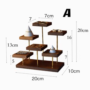 May include: A wooden jewelry display stand with five tiers. The stand is 20 inches wide and 10 inches tall. The stand has a gold metal frame and is made of dark wood.